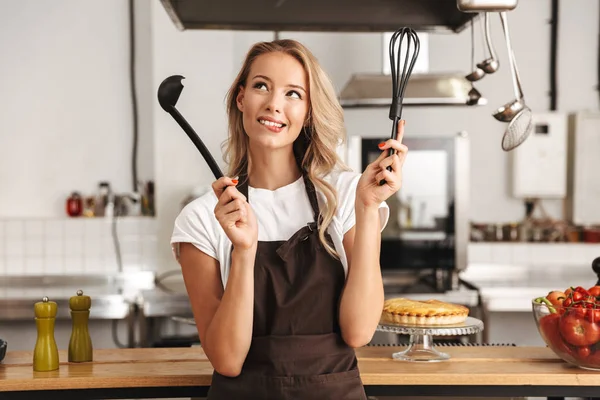 Lachende Jonge Vrouw Chef Kok Schort Staande Keuken Holding Pollepel — Stockfoto