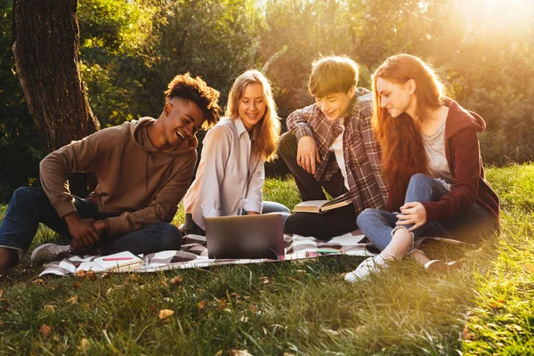 ラップトップ コンピューターを使用して 公園で一緒に宿題をやって Multhiethnic 学生の笑顔グループ — ストック写真