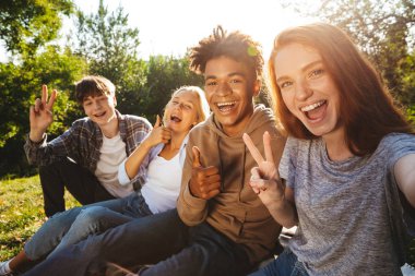 Grup öğrencinin cep telefonu ile bir selfie alarak parkta birlikte ödev mutlu multhiethnic