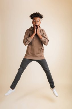Heyecanlı genç afro Amerikalı adam portresi tam uzunlukta izole atlama hoodie giyinmiş