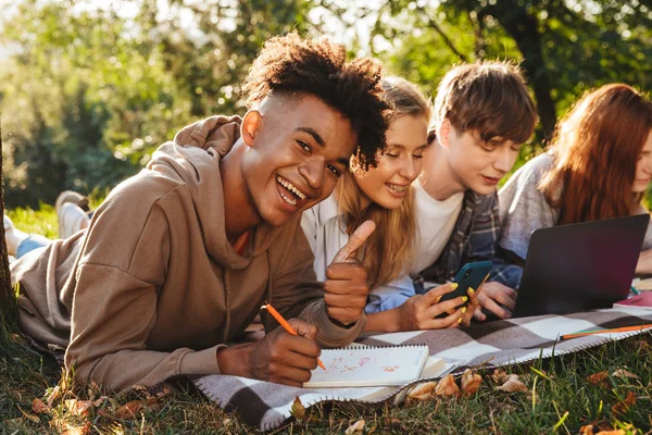 Gruppo Studenti Multietnici Ridenti Che Fanno Compiti Insieme Parco Usando — Foto Stock