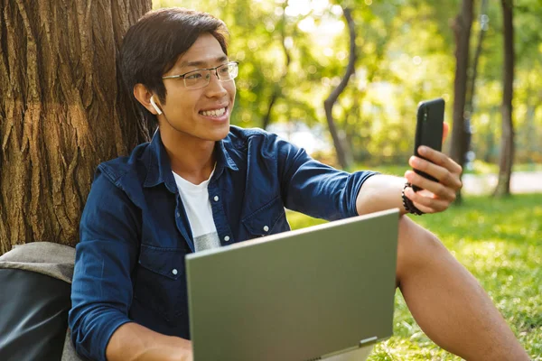 Feliz Asiático Masculino Estudante Óculos Fazendo Selfie Smartphone Segurando Laptop — Fotografia de Stock