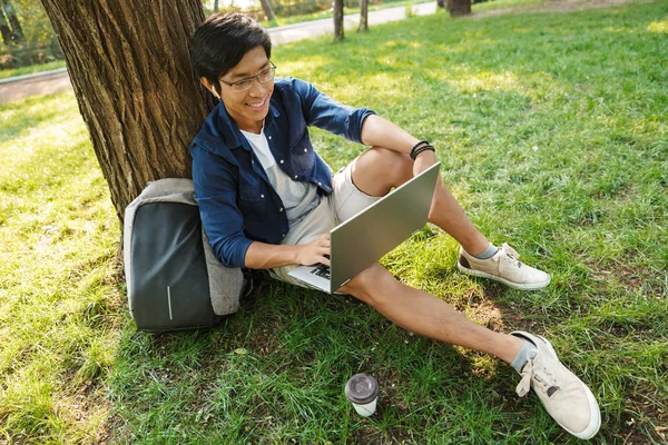 Feliz Asiático Masculino Estudante Óculos Usando Laptop Computador Enquanto Sentado — Fotografia de Stock