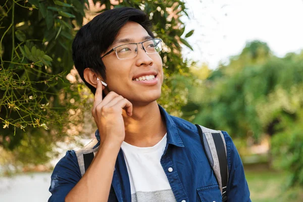 Imagem Smiling Asiático Estudante Masculino Óculos Ouvindo Música Olhando Para — Fotografia de Stock