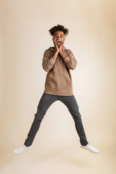一个兴奋的年轻黑人美国男子的全长肖像穿着帽衫跳跃孤立 — 图库照片