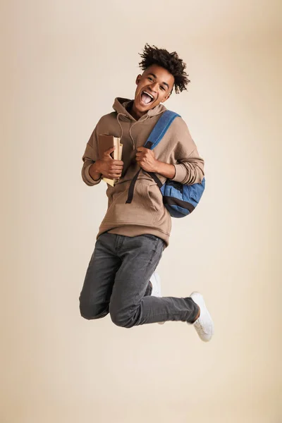 全长肖像一个微笑的年轻美国黑人男子穿着帽衫背着背包隔离 持有书籍 — 图库照片
