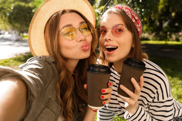 Duas Jovens Amigas Sorridentes Divertindo Parque Tirando Uma Selfie Segurando — Fotografia de Stock