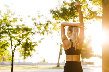 Arkadan Görünüş fotoğraf güzel genç sarışın kadın Park açık havada germe egzersizleri yapmak spor..