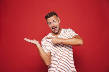 İyimser adam 30'lu çizgili tişört el işaret parmakları, boşaltmak izole kırmızı arka plan üzerinde onun Palm'da