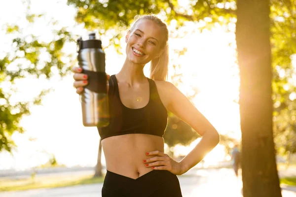 公園の保有物水をボトルで驚くほど興奮して若い金髪スポーツ女性のイメージ — ストック写真