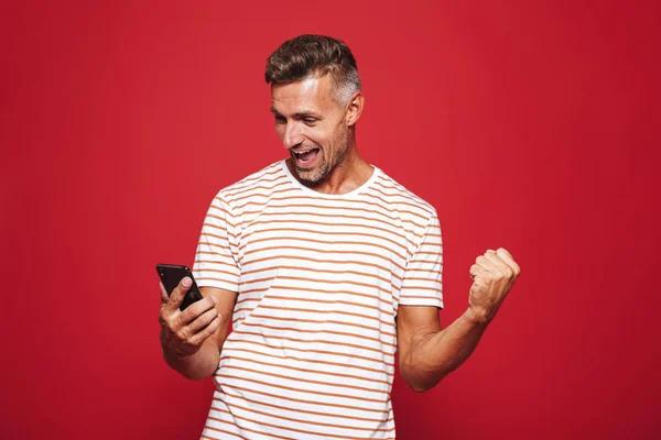 Retrato Hombre Sonriente Pie Sobre Fondo Rojo Mirando Teléfono Móvil — Foto de Stock