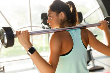 Sakinliğin arkadan görünüm ile halter egzersiz yaparak ve uzak seyir spor salonunda kadın spor