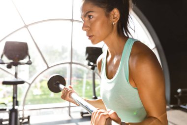 Ciddi yan görünüm ile halter egzersiz yaparak ve uzak seyir spor salonunda kadın spor