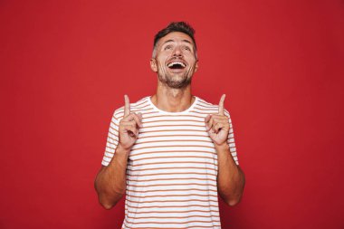 Çizgili tişört el işaret parmakları yukarı boşaltmak izole kırmızı arka plan üzerinde mutlu adam