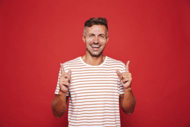 Çizgili tişört el işaret parmakları yukarı boşaltmak izole kırmızı arka plan üzerinde de olumlu adam