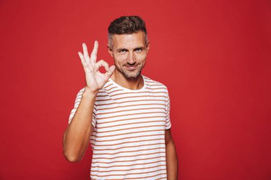 Gülümseyen ve ok işareti izole kırmızı arka plan üzerinde gösterilen çizgili tişört çekici adam