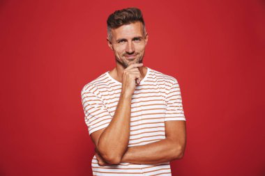 Beyaz adam düşünme ve kırmızı arka plan üzerinde izole çene dokunmadan çizgili tişört