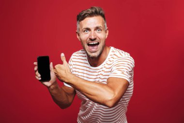 Kutlama, yaşasın vererek kırmızı arka plan üzerinde duran, cep telefonu, gösterilen bir heyecanlı bir adam portresi