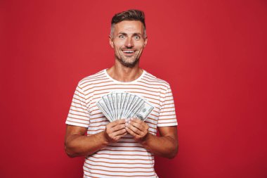 Kırmızı arka plan üzerinde duran, para banknot tutan memnun adam portresi