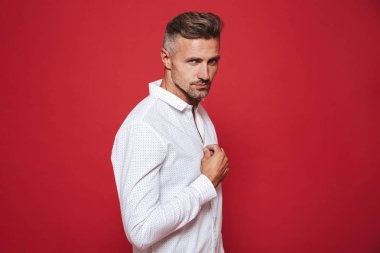Yetişkin beyaz adamla 30'lu anız beyaz gömlek kırmızı arka plan üzerinde izole kamera üzerinde seyir