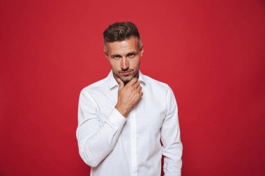 Yakışıklı adam anız beyaz gömlek kırmızı arka plan üzerinde izole kamera seyir ile