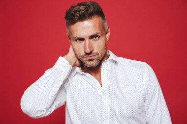 Erkeksi ciddi 30'lu yaşlarda olan adam anız beyaz gömlek kırmızı arka plan üzerinde izole kamera seyir portresi