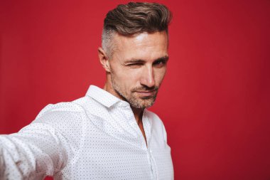 Erkeksi ciddi adam 30'lu yaşlarda beyaz gömlekli selfie fotoğrafta kırmızı arka plan üzerinde izole