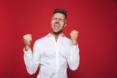 Bağırarak ve kırmızı arka plan üzerinde izole yumruk kenetlenmesi formal giyim iyimser adam fotoğrafı