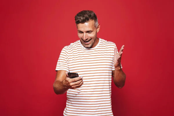 Retrato Homem Alegre Sobre Fundo Vermelho Olhando Para Telefone Móvel — Fotografia de Stock