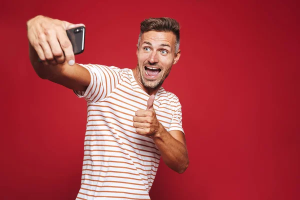 Portret Wesoły Człowiek Stojąc Czerwonym Tle Biorąc Selfie Dając Kciuk — Zdjęcie stockowe