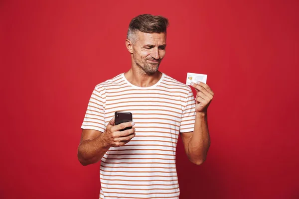 Retrato Hombre Decepcionado Pie Sobre Fondo Rojo Sosteniendo Teléfono Móvil — Foto de Stock