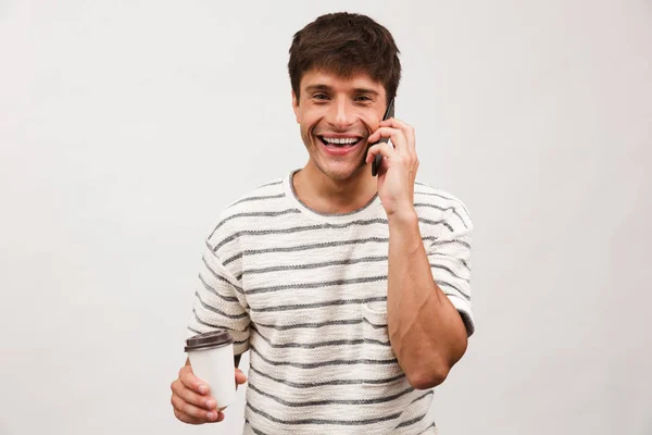 形象的快乐开朗英俊的人站在白色背景墙上喝咖啡用手机交谈 — 图库照片