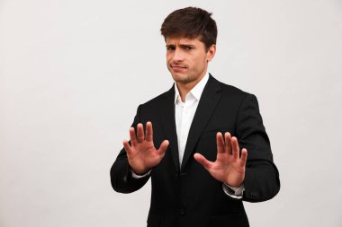 Dur jest yapmak imge-in beyaz arka plan duvardan izole ayakta ciddi genç işadamı.