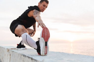 Yakışıklı güçlü genç sporcu açık havada germe egzersizleri beach yapmak, görüntü.