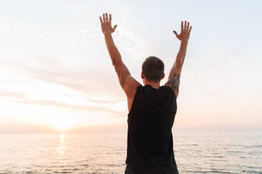 Açık havada germe egzersizleri beach yapmak, yakışıklı güçlü genç sporcunun görünüm görüntüsü geri.