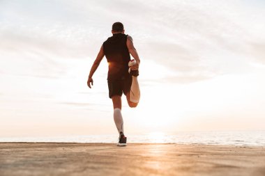 Yakışıklı güçlü genç sporcu açık havada germe egzersizleri beach yapmak, görüntü.