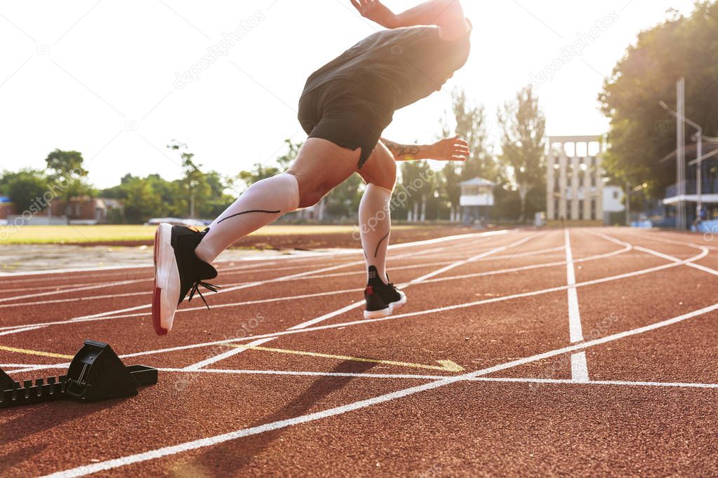 Image of handsome strong young sportsman running outdoors at the beach.