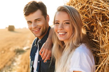 Romantik Çift erkek ve altın sahada yürüyüş ve büyük haystack ayakta kadın resim