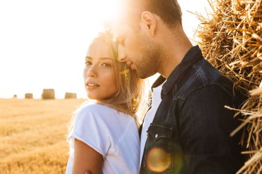 Resmi İhale çift erkek ve kadın hasat ve büyük haystack ayakta sonra altın sahada yürüyüş