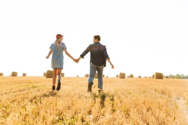 Arkadan Görünüş mutlu bir genç çiftin birlikte el ele tutuşarak buğday alan yürüyüş