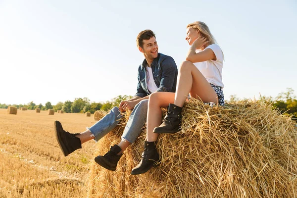 Sorridente Giovane Coppia Seduta Insieme Pagliaio Campo — Foto Stock