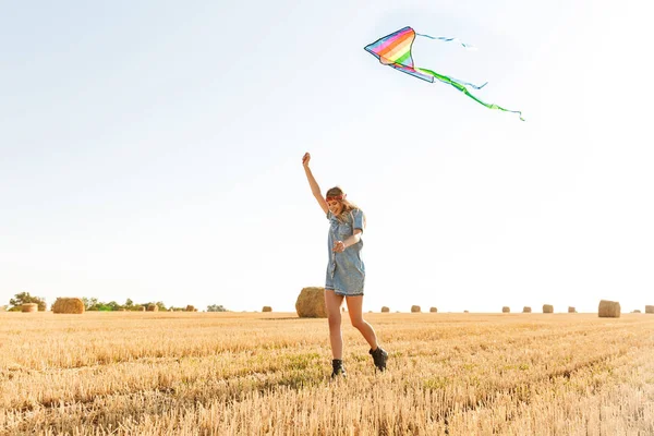 日当たりの良い日中ゴールデン フィールド歩く微笑し 中に凧が飛んで遊ぶの 代のスタイリッシュな女性の肖像 — ストック写真