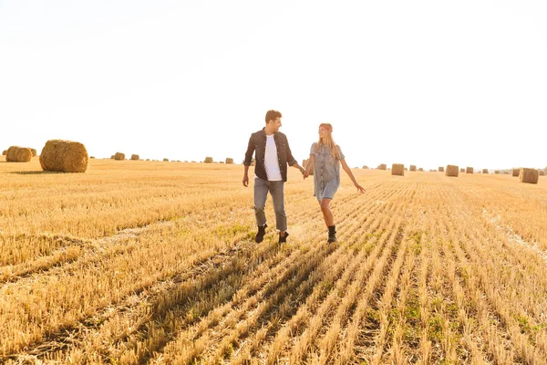 Счастливая Молодая Пара Идущая Вместе Пшеничному Полю Держась Руки — стоковое фото