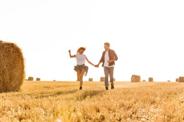 Görüntü güzel erkek ve kadın haystacks grup ile altın alan aracılığıyla güneşli gün boyunca çalışan