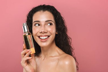 Pembe arka plan üzerinde izole portre oldukça mutlu neşeli güzel genç kadının poz petrol tutarak onun cilt dikkat çekmek.