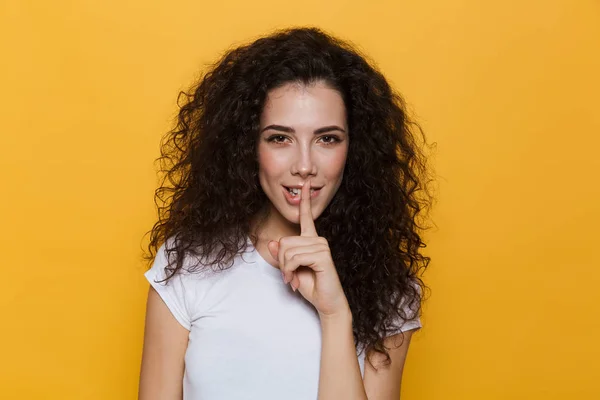 黄色背景に分離の唇に指を押し巻き毛を持つ魅力的な女性 代のイメージ — ストック写真