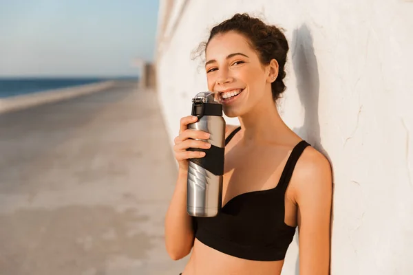 Smiling Young Sportswoman Standing Outdoors Seaside Leaning Wall Holding Water — Stock Photo, Image