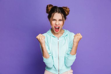 Sevindirici ve yumruklarını Studio violet arka plan üzerinde izole başarısında kenetlenmesi iki buns ile neşeli güzel kadın portresi