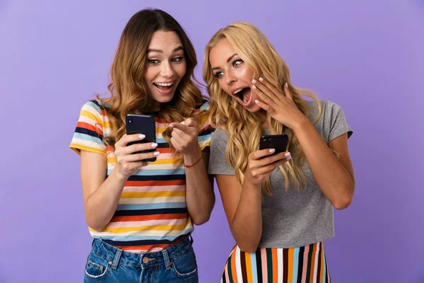Две Довольно Веселые Юные Подруги Стоят Изолированно Фиолетовом Фоне Используя — стоковое фото