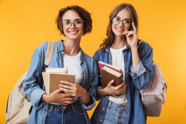 Neşeli mutlu duygusal genç kadın arkadaş poz fotoğraf kitap tutan sarı arka plan üzerinde izole.